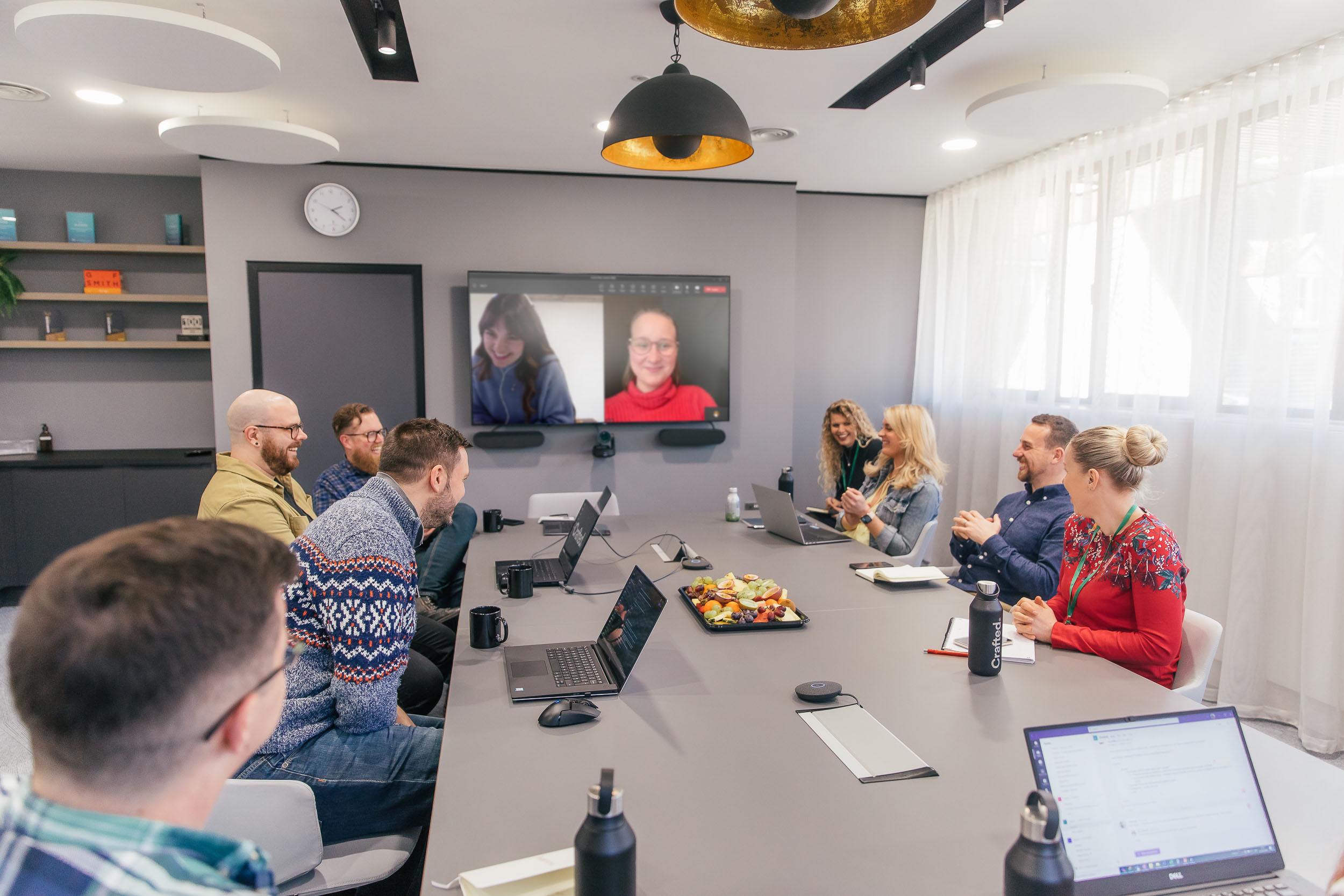Crafted team working in large meeting room with others dialled in.