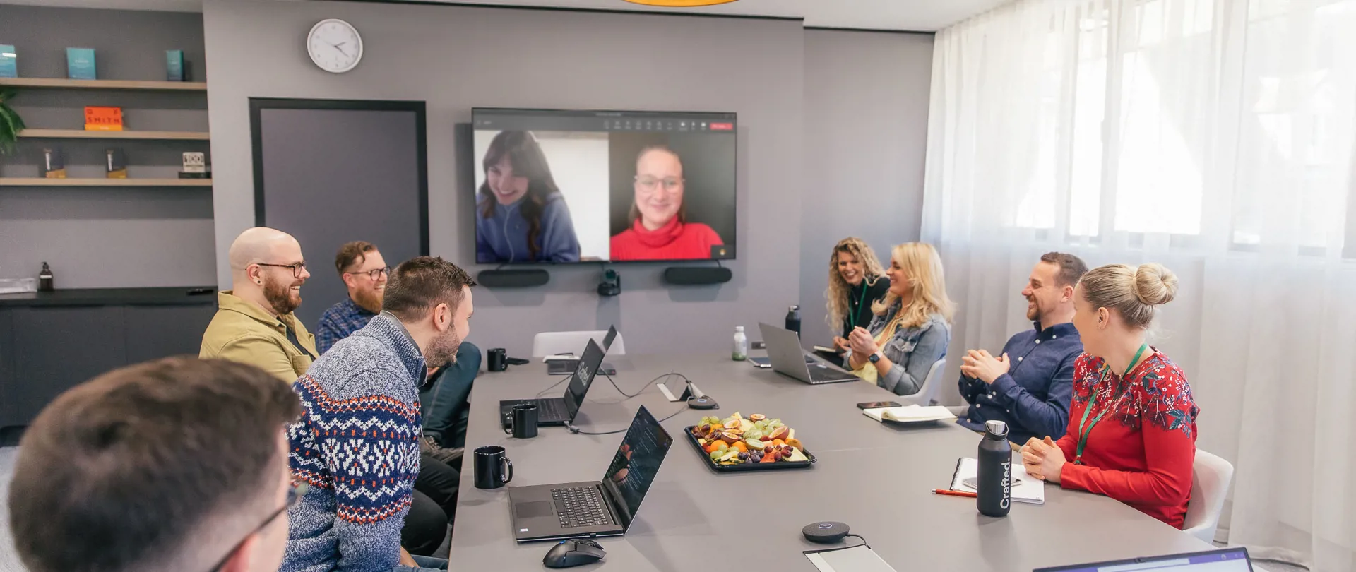 Crafted team working in large meeting room with others dialled in.