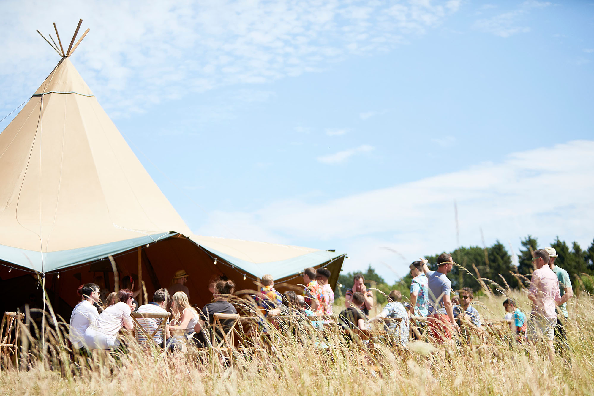 Crafted team enjoying the Summer party at large outside tipi with blue sky 
