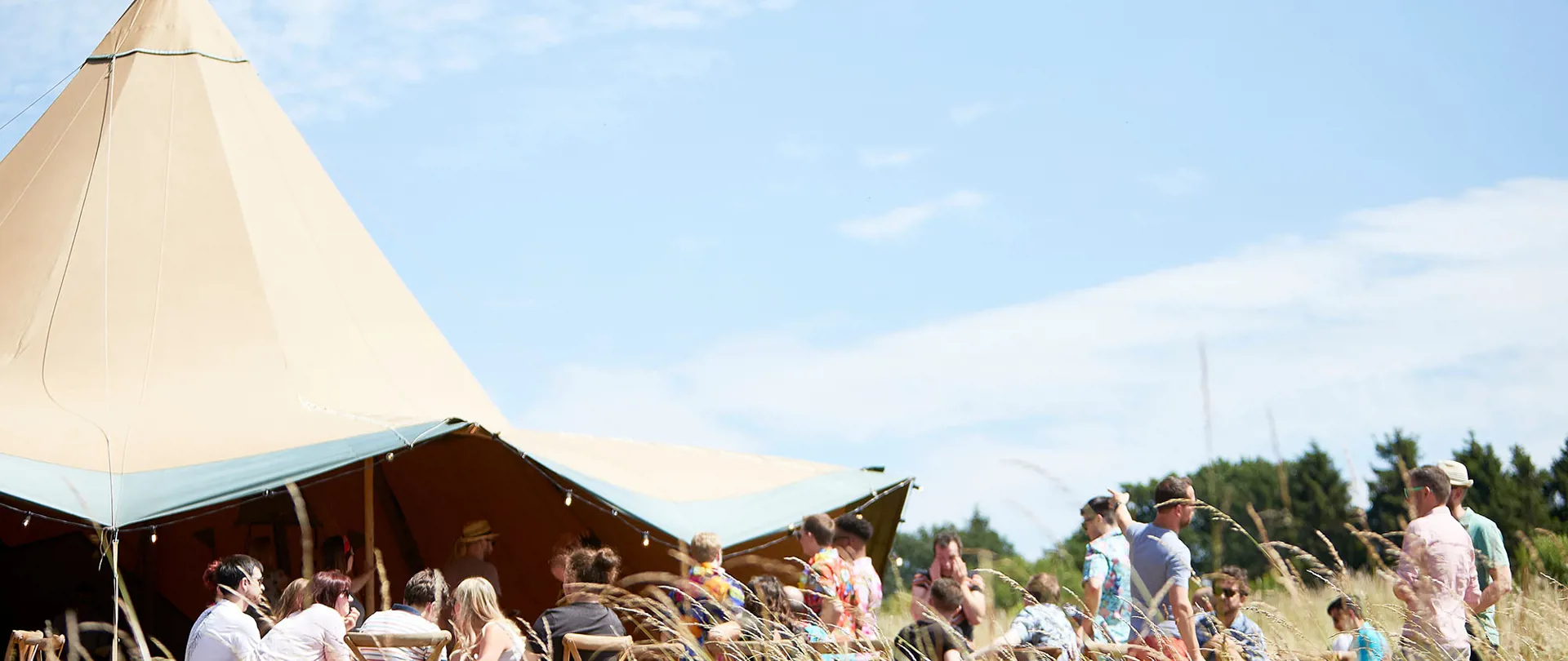 Crafted team enjoying the Summer party at large outside tipi with blue sky