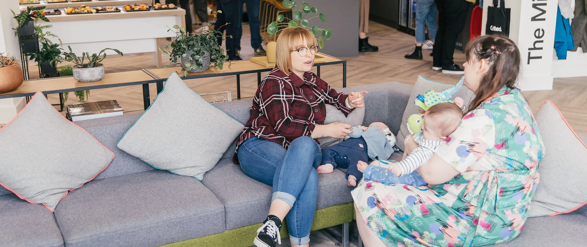 Two Crafted team members with their babies on the sofa in the Crafted office.
